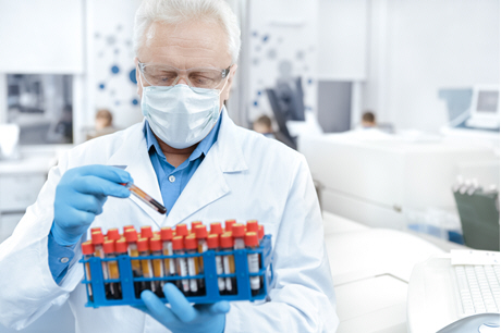 doctor in white lab coat holds rack of blood samples
