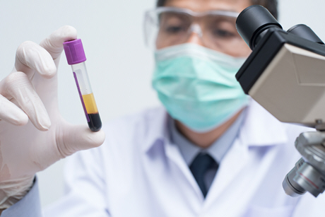 doctor looking centrifuged blood in test tube with microscope in laboratory