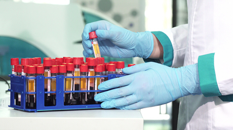 doctor taking tube of blood among rack