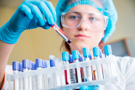 female doctor examines blood sample from rack