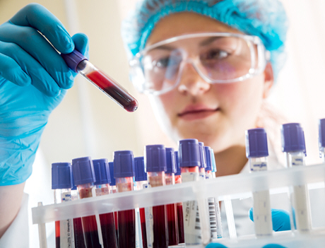 female doctor looks at blood from rack of tubes